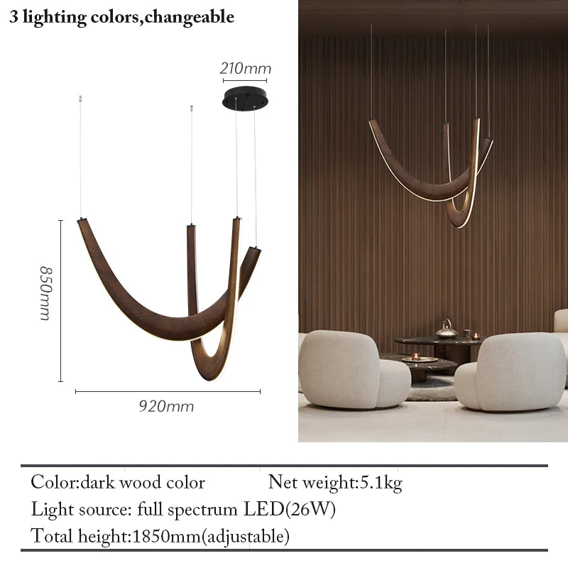 The Double Curve Wood Pendant Light, featuring a dark wood finish, hangs in a lounge with two white chairs and a small table. A diagram displays the dimensions and main specs of this handcrafted lighting fixture.