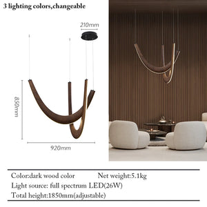 The Double Curve Wood Pendant Light, featuring a dark wood finish, hangs in a lounge with two white chairs and a small table. A diagram displays the dimensions and main specs of this handcrafted lighting fixture.