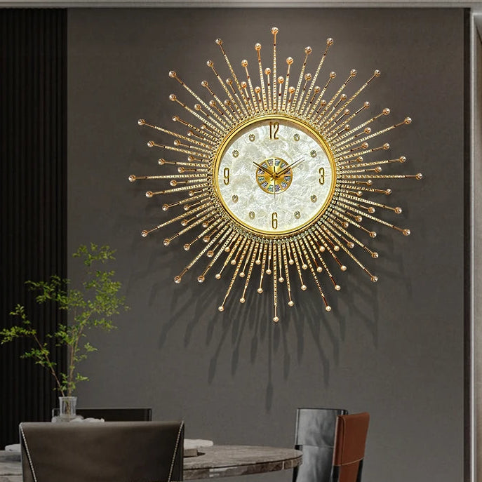 The Premium Sun Wall Clock with a gold sunburst design and decorative face hangs above a dining table with chairs, lush plants, and tableware in a modern room.