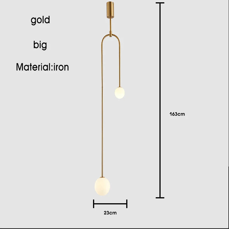 The Minimalist Line Light is a gold iron pendant fixture with two spherical bulbs, measuring 163cm in height and 23cm in width. This modern piece offers a minimal mounting system, perfect for any contemporary space.