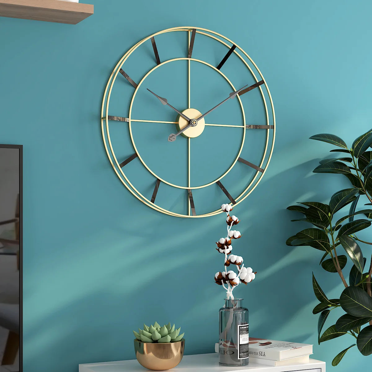 A large, modern gold geometric design wall clock on a teal wall above a decorative shelf with plants and books.
