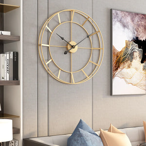 A contemporary vibes gold geometric design wall clock on a gray textured wall above a blue pillow and beige sofa.