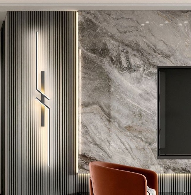 Modern interior featuring a marble accent wall, vertical slatted paneling, the Minimalist Wall Sconce with a geometric design, and a brown upholstered chair in the foreground.