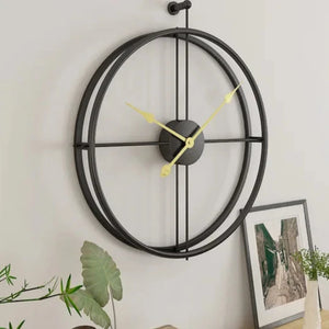 A large, modern minimalist ring wall clock with a simple design in black and yellow, mounted on a light-colored wall beside framed artwork and green plants.