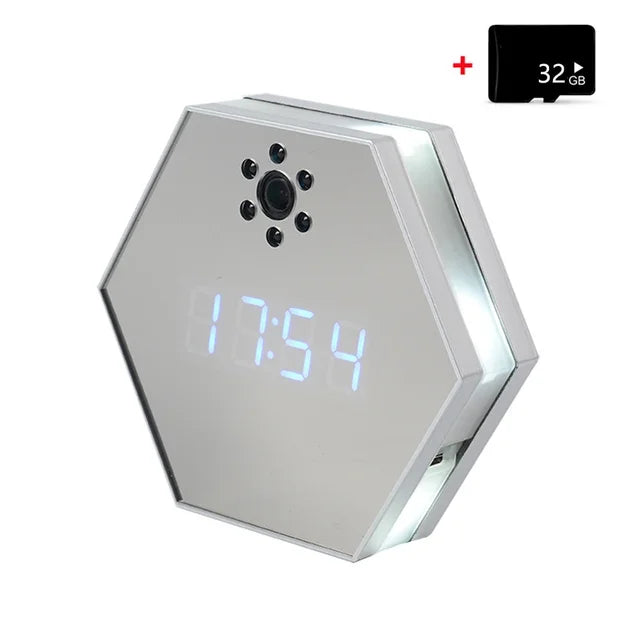 The Sleek Clock SpyCam is a hexagonal digital clock with a mirrored face, built-in spy camera with multiple lens holes, 4K HD resolution, and comes with a 32GB microSD card. The display shows the time "17:54.