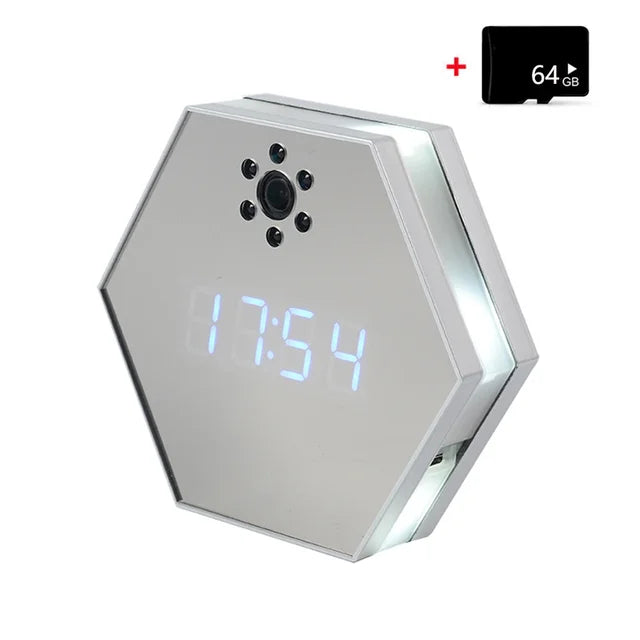 The Sleek Clock SpyCam is a hexagonal digital clock with a mirrored display showing 17:54, featuring a spy camera lens above the display, 4K HD video clarity, and a 64GB memory card in the top right corner.